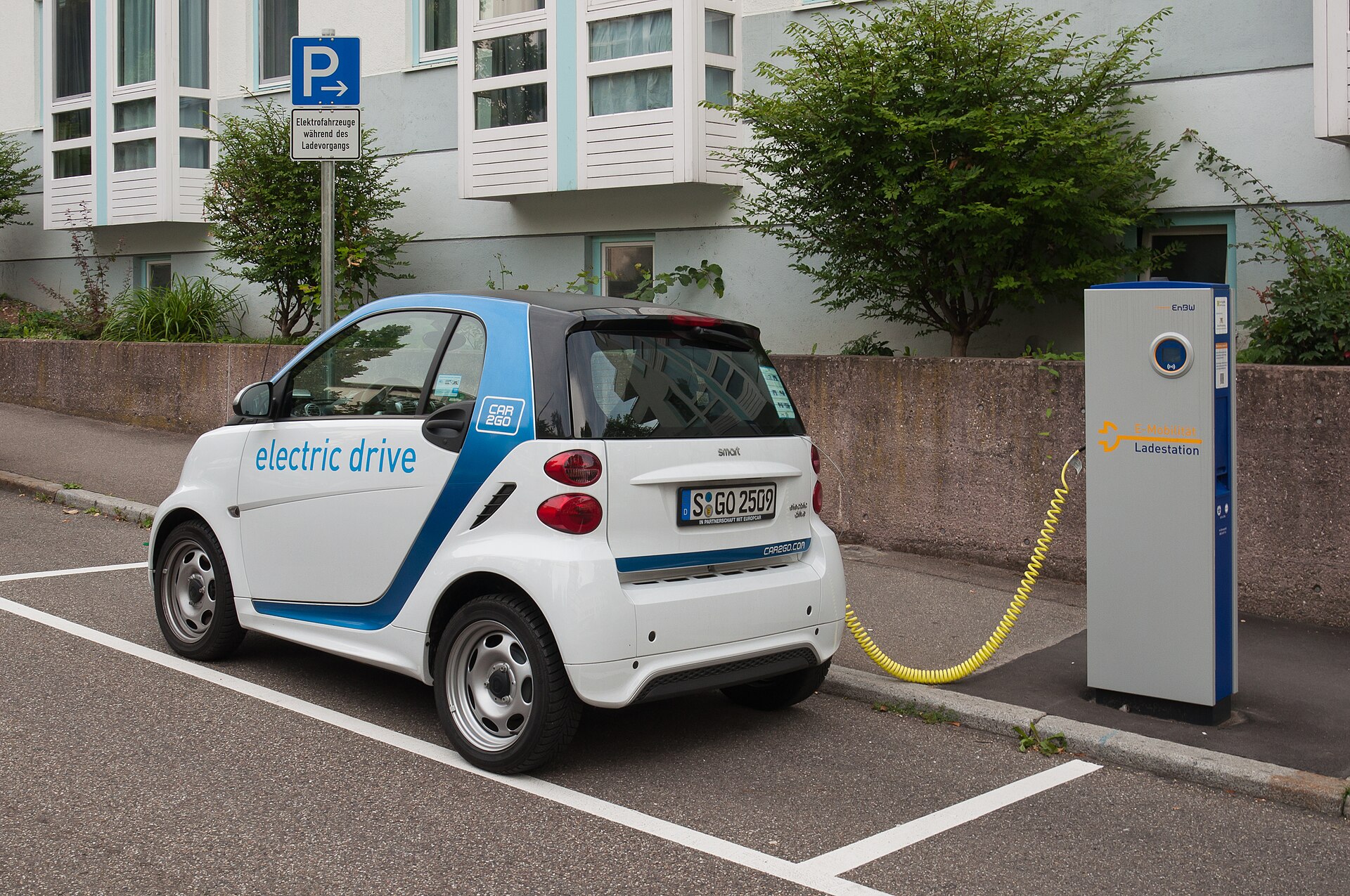 A modern electric sedan and a hybrid SUV parked side by side at a charging station.