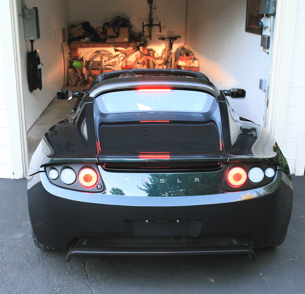An electric vehicle plugged into a home wall-mounted Level 2 charger in a residential garage.