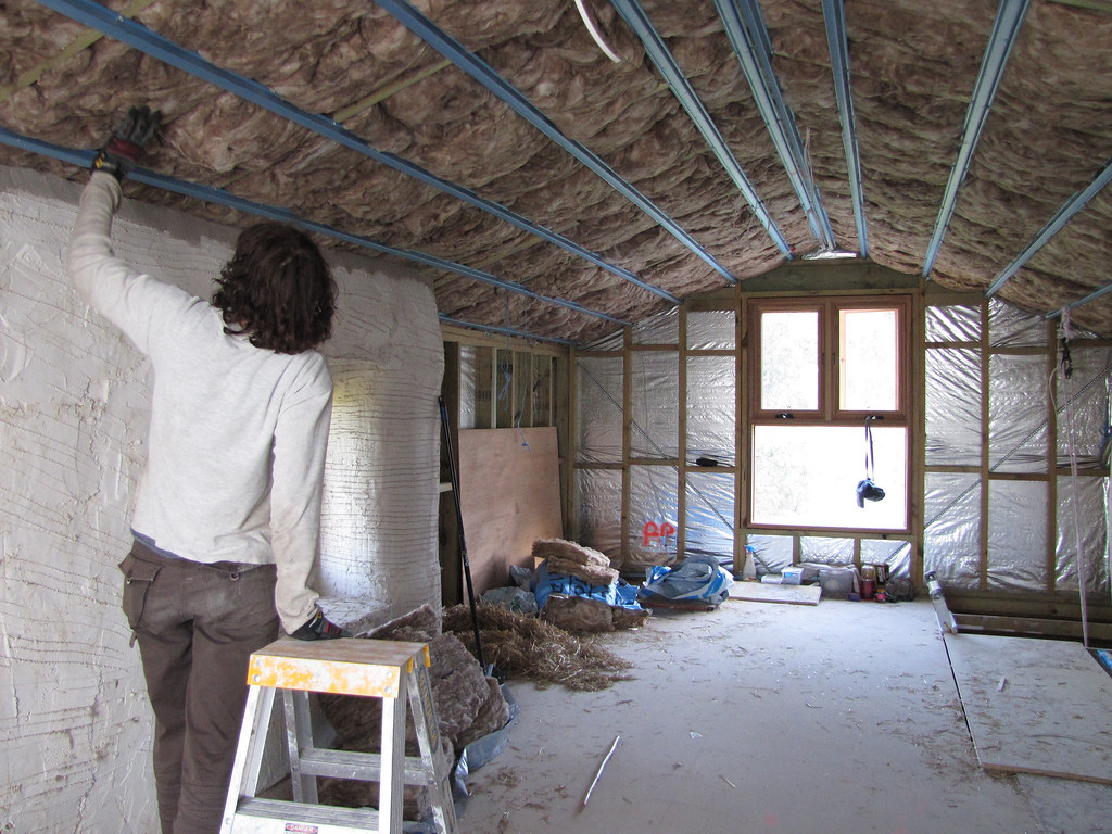 An energy auditor using a blower door fan in the front entry of a house to test air leakage.