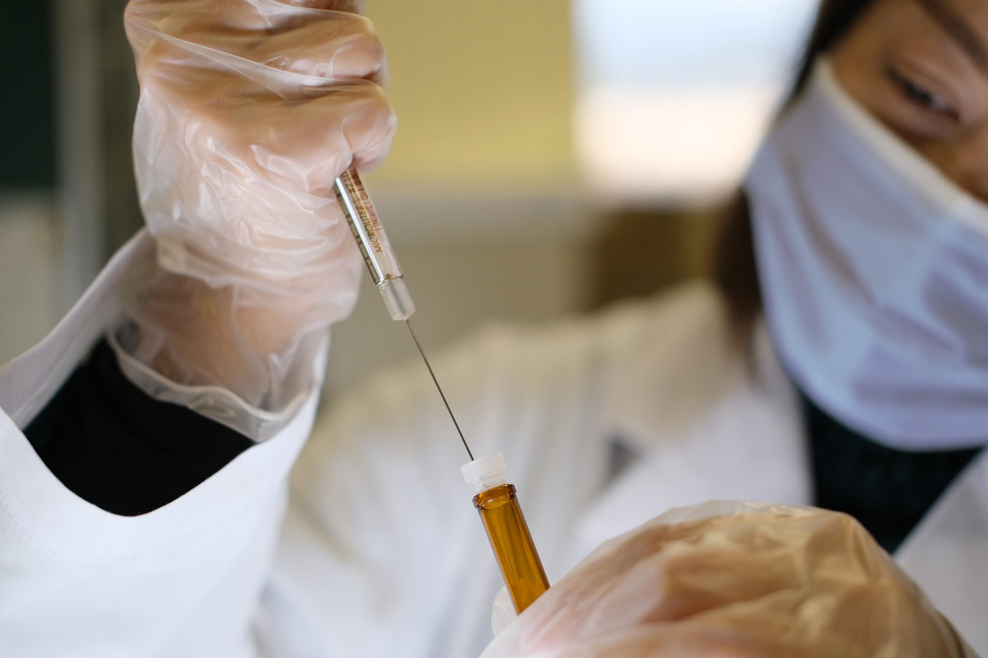 A researcher in a laboratory preparing a vaccine vial for analysis.